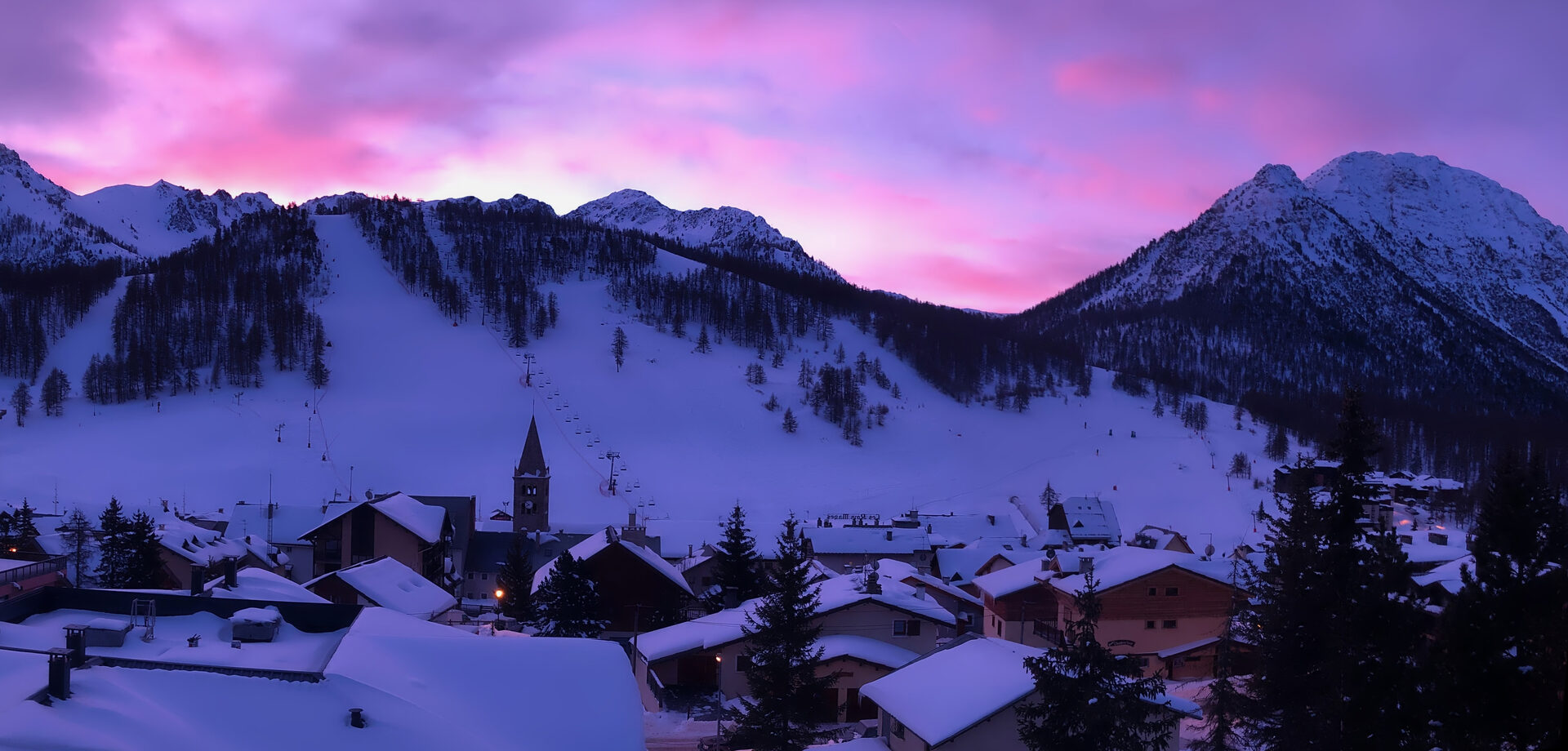Montgenèvre au crépuscule — vue sur le village, les pistes et les crêtes enneigées